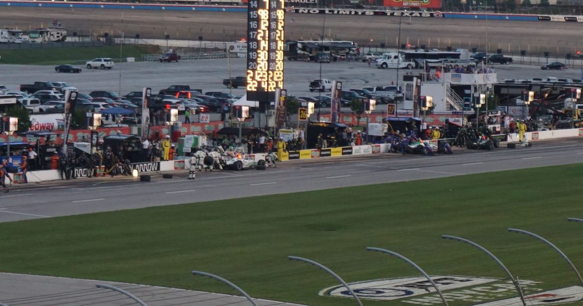 an IndyCar on a road course, ideally in a context that visually contrasts with typical F1 imagery — heavier bodywork, aeroscreen visible