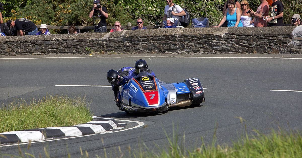 a sidecarcross outfit racing off-road, showing both driver and passenger working together