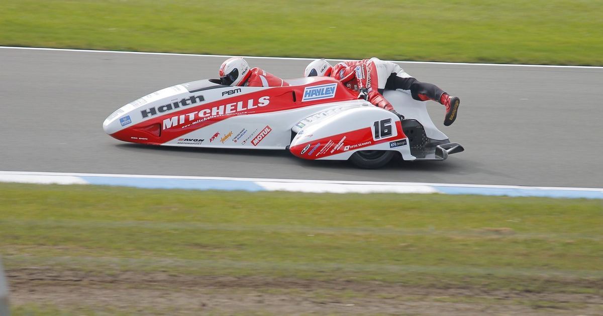 an experienced sidecar racing crew, driver and passenger together, illustrating the partnership newcomers would need to join