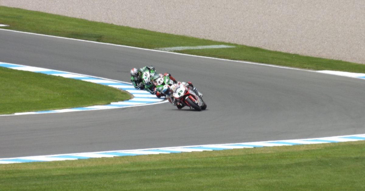 a World Superbike machine cornering at lean, contrasted conceptually against typical MotoGP prototype imagery