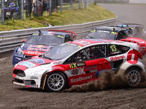 a rallycross car on a mixed tarmac-and-gravel circuit, illustrating the discipline's rally-derived origins