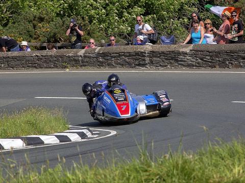 a sidecarcross outfit racing off-road, showing both driver and passenger working together
