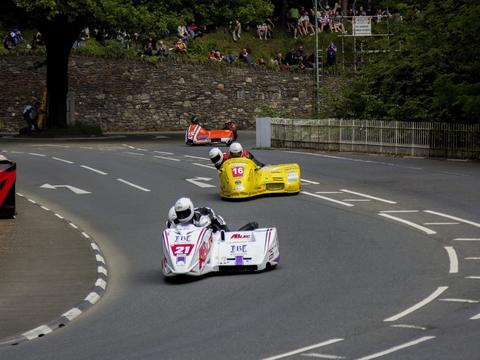 a sidecar passenger visibly working alongside the driver during a race, illustrating the two-person coordination