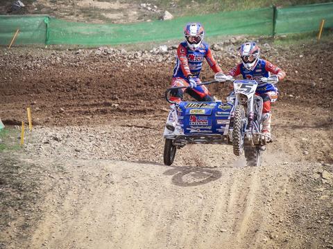 A sidecarcross outfit racing on a dirt motocross track