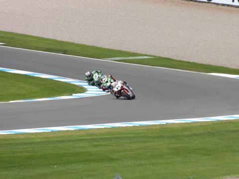 a World Superbike machine cornering at lean, contrasted conceptually against typical MotoGP prototype imagery