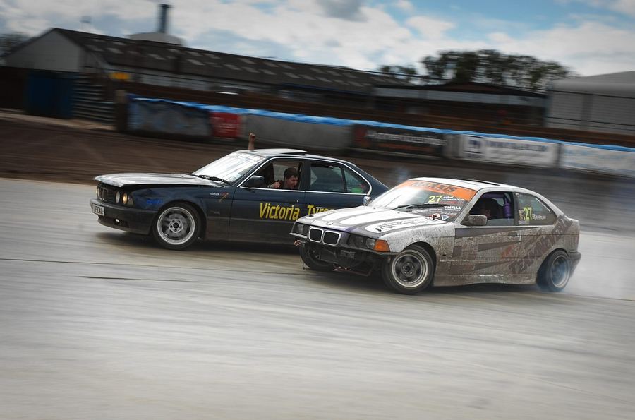 Two drift cars running a tandem battle nose-to-tail through a corner