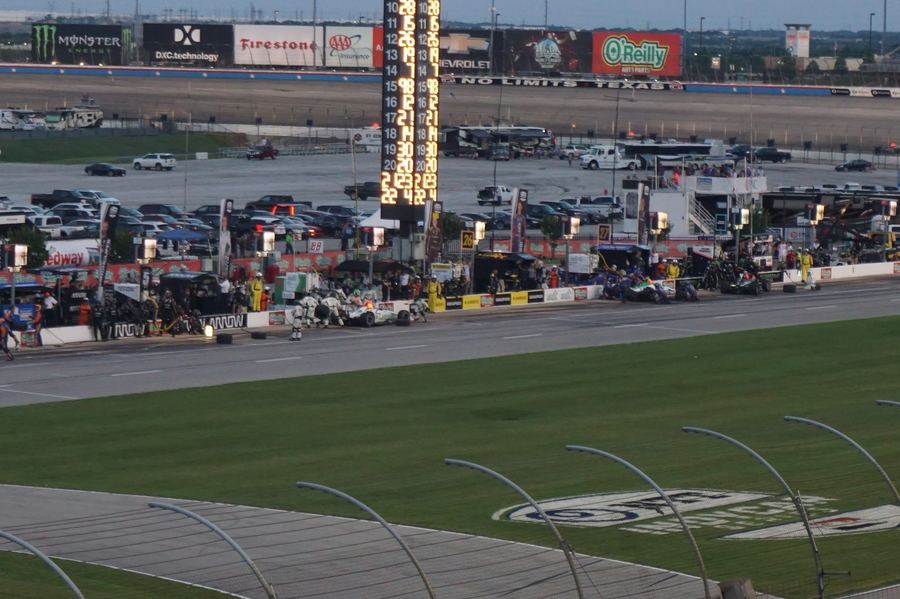 an IndyCar on a road course, ideally in a context that visually contrasts with typical F1 imagery — heavier bodywork, aeroscreen visible