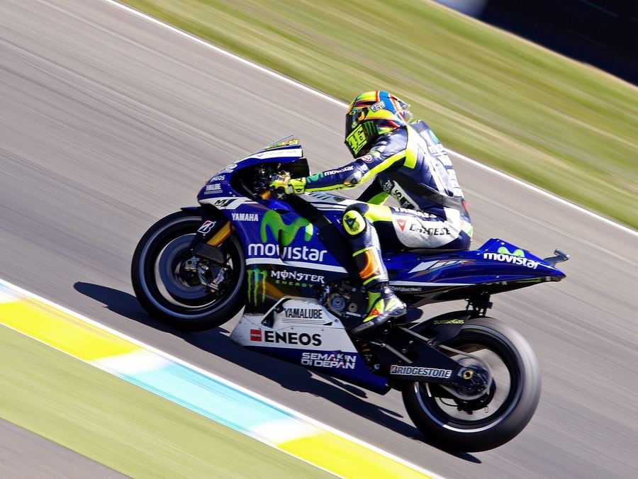 A MotoGP rider navigating a corner, demonstrating the full-body physical effort required to manage lean angle throughout a race distance