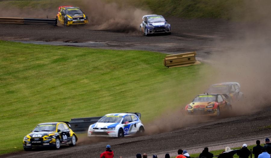 a rallycross car jumping on a mixed-surface circuit, contrasted conceptually against a WRC car on a rally stage