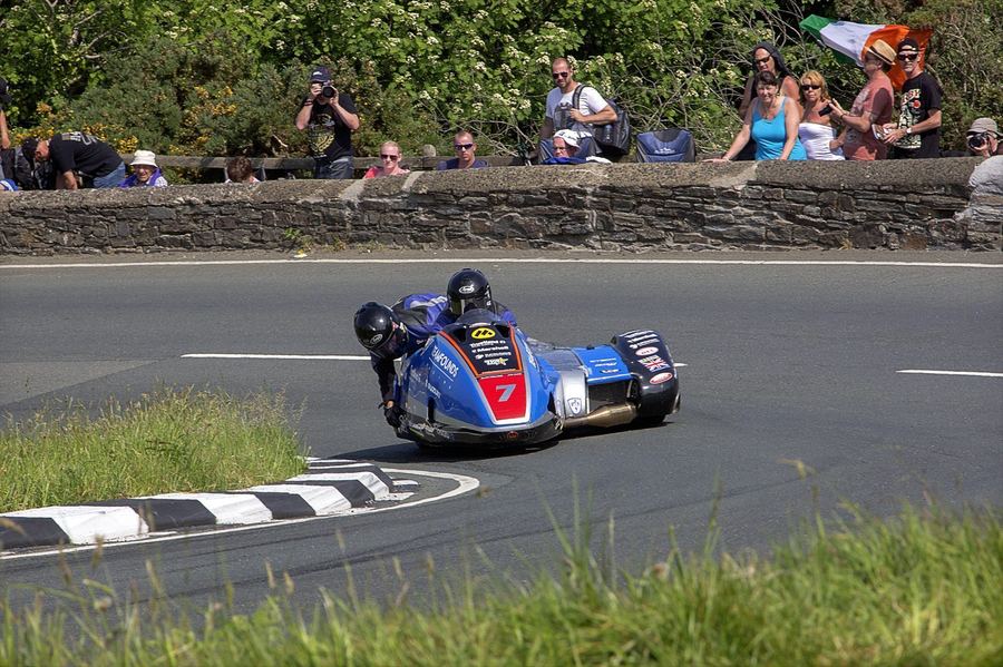 a sidecarcross outfit racing off-road, showing both driver and passenger working together
